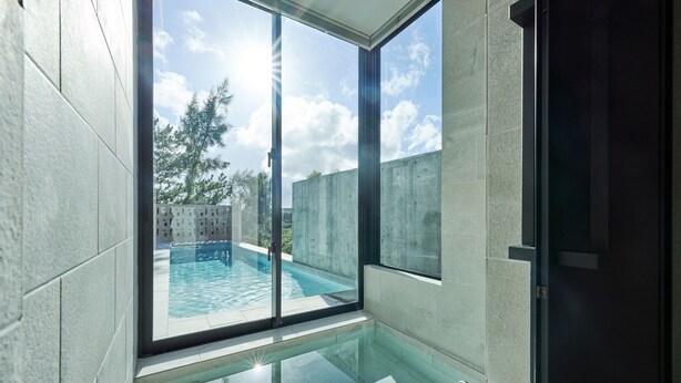 A modern bathroom with a glass-enclosed shower and a view of an outdoor swimming pool. - ima villa (Onna)