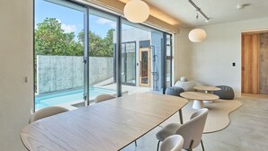 A modern interior with a dining area, large windows, and a view of a swimming pool. - ima villa (Onna)