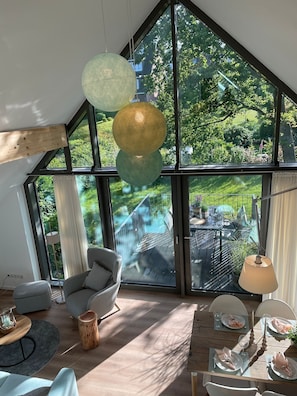 Ein modernes Interieur mit großen Fenstern, einem Essbereich und Blick auf einen Garten.