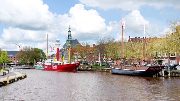 A harbor with boats, a church steeple, and red-brick buildings.