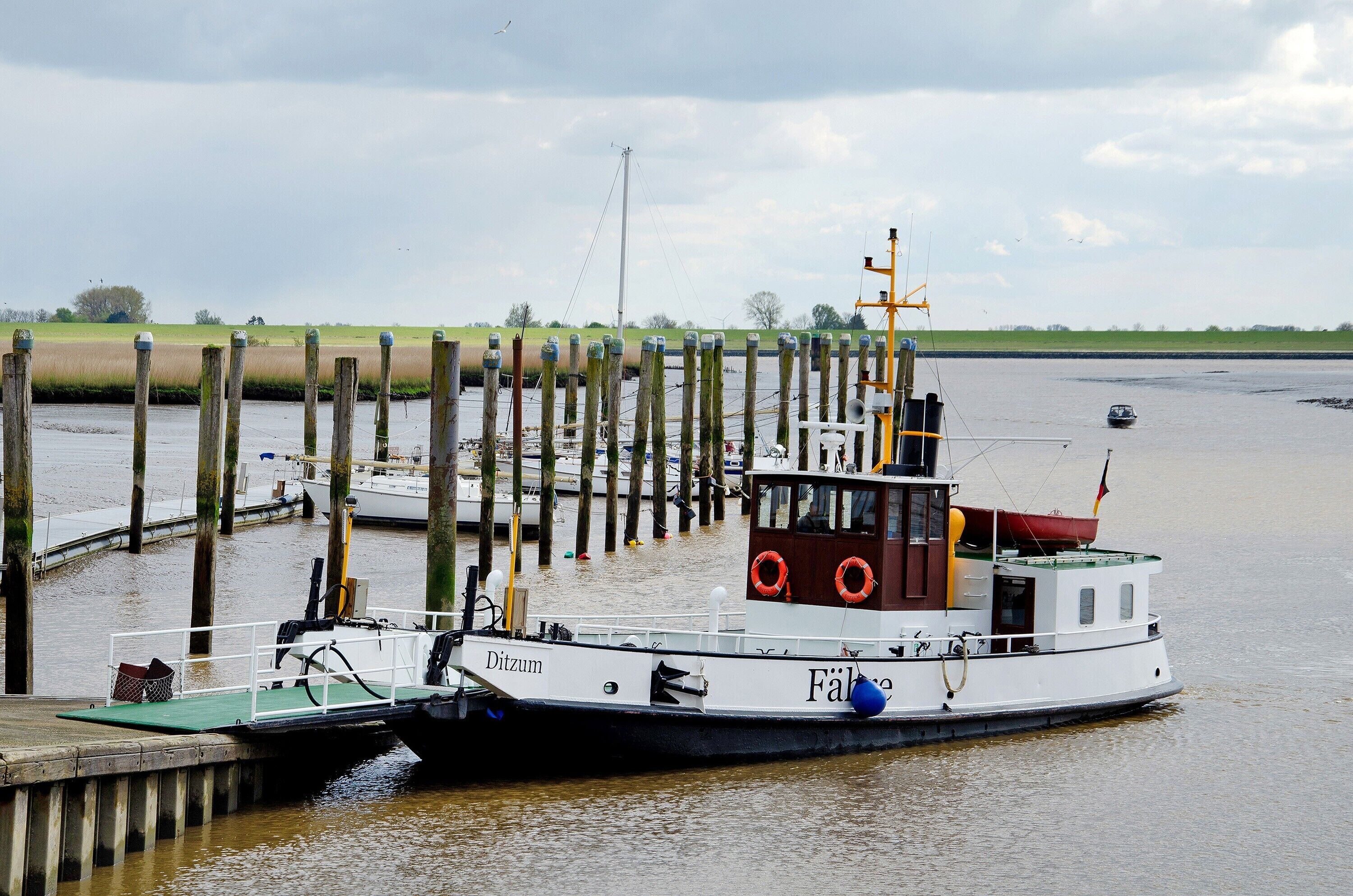 A boat docked at a pier with a wooden structure in the background.