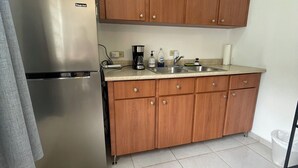 A compact kitchen with wooden cabinets, a stainless steel refrigerator, a coffee maker, and a sink. - Where Bad Bunny is from - Cozy Mountain Valley Villa Vega Baja with AC, WiFi (Vega Baja)