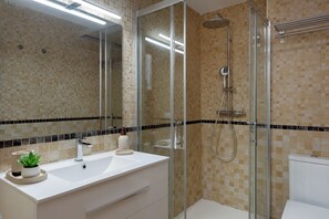 Une salle de bain moderne avec une douche à parois de verre, un lavabo blanc et un miroir.