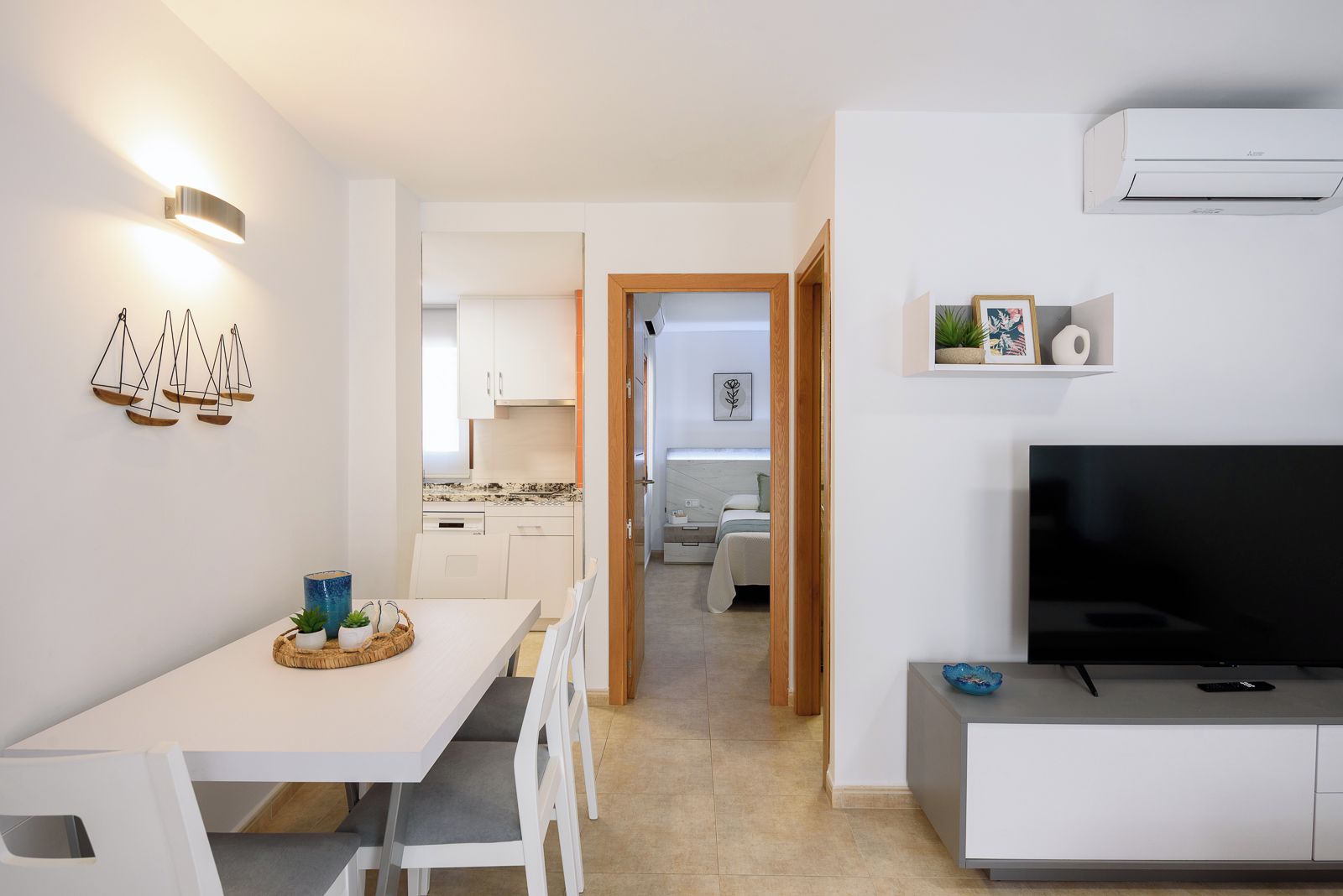 A modern apartment with a dining area, kitchenette, living room, and a TV.