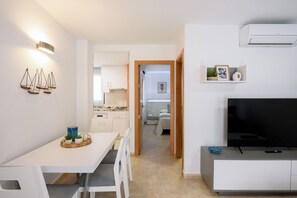 Un appartement moderne comprenant un coin repas, une kitchenette, un salon et un téléviseur.