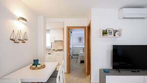 Eine moderne Wohnung mit Essbereich, Küchenzeile, Wohnzimmer und Fernseher.