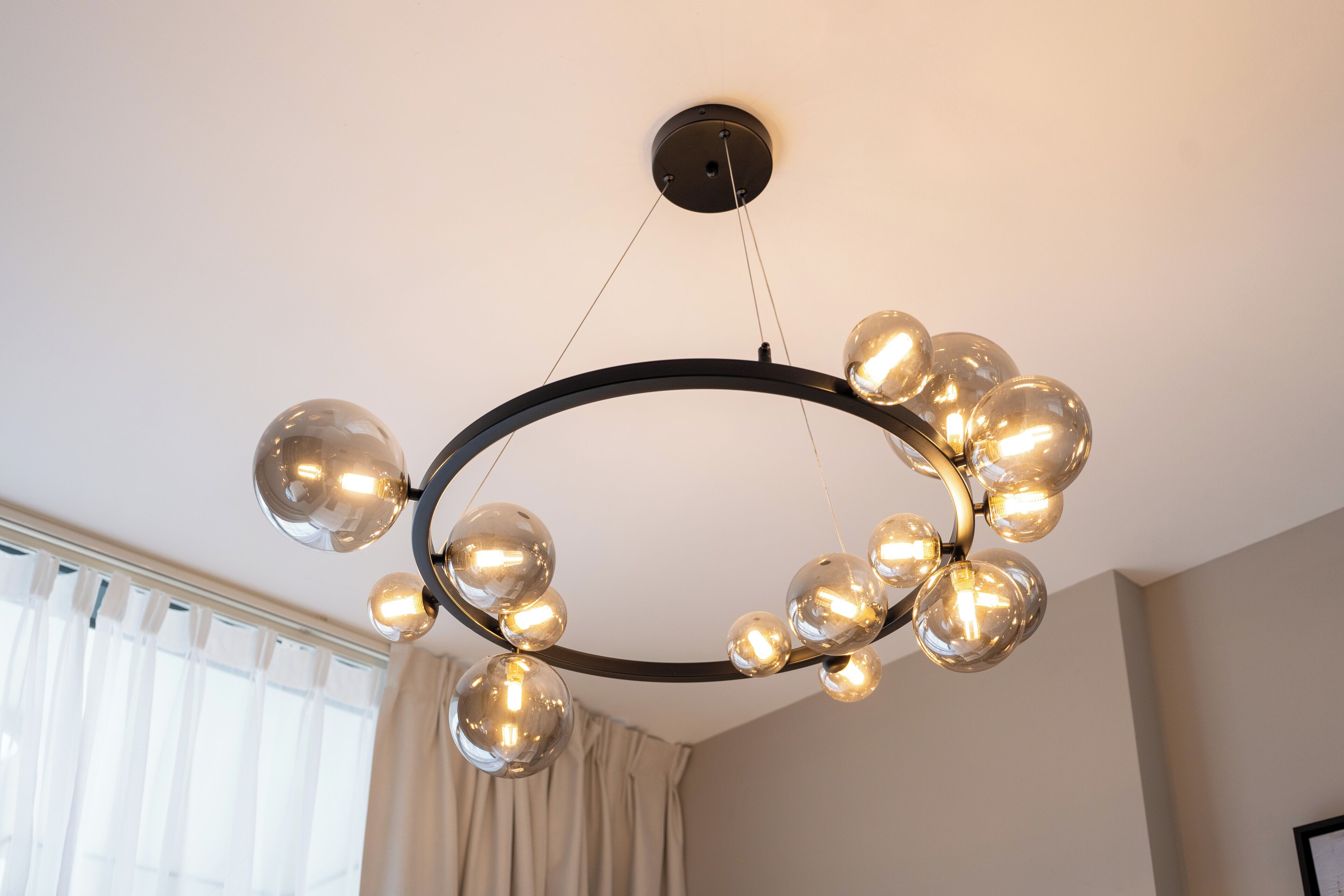 A modern chandelier with multiple spherical glass bulbs suspended from a circular metal frame.