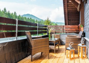 A wooden deck with wicker furniture, a glass table, and lanterns. - Gasthof Kanzlersgrund (Steinbach-Hallenberg)