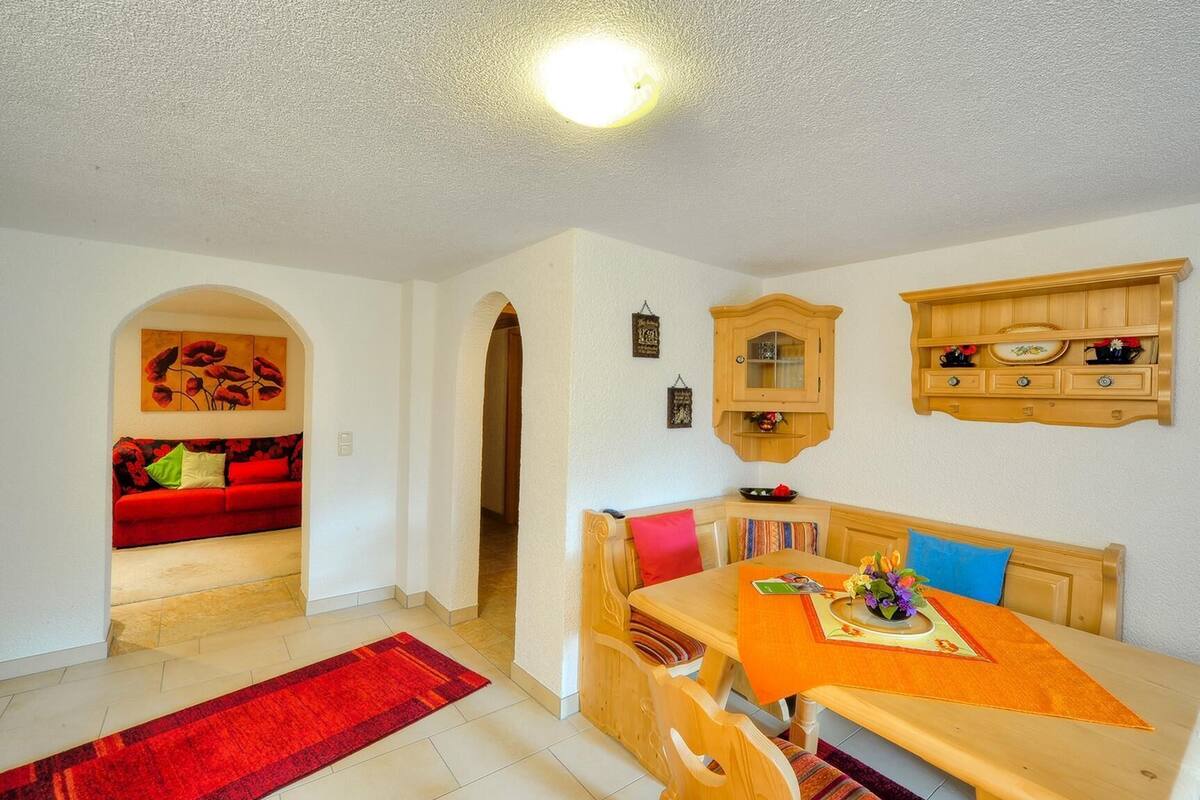 A cozy living room with a red sofa, wooden dining table, and a red rug.