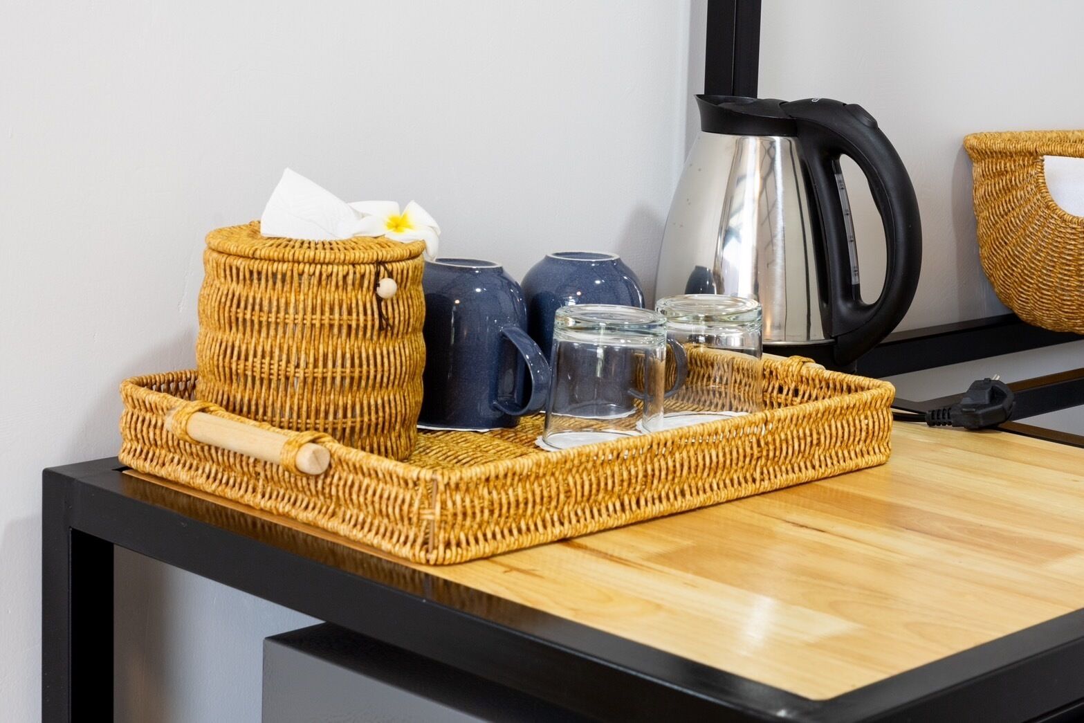 A wicker tray with a wooden rolling pin, a white cloth, and a flower on a wooden table.