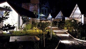 Een nachtzicht van een resort met een verhard pad dat naar een gebouw met een schuin dak leidt.