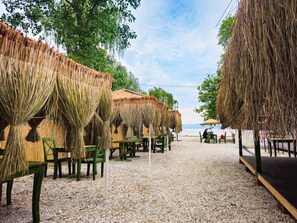 A beachside restaurant with thatched umbrellas and wooden tables. - İznik Seyir Kamp (Iznik)
