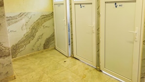 Tres puertas de baño con paredes de mármol y suelo de baldosas.
