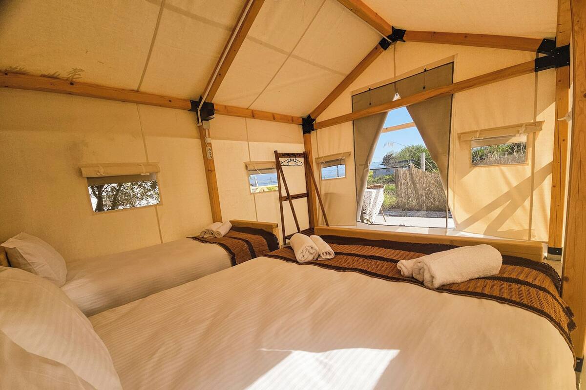 Um quarto tipo tenda com duas camas, uma escada e janelas.