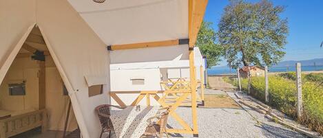 Alojamiento con carpa, una mesa y sillas, vista al mar y una estructura de madera.