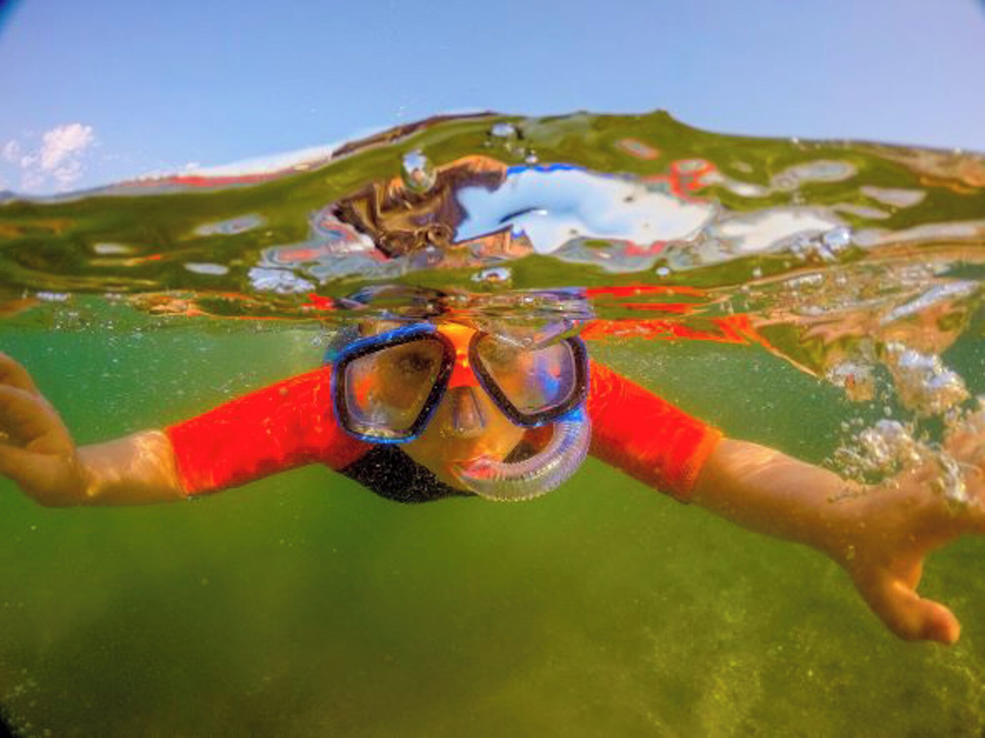 A person swimming underwater with goggles.