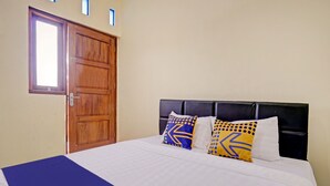 A hotel room with a large bed, a wooden door, and a window. - SPOT ON 90577 Griya Afifah Syariah (Klaten)