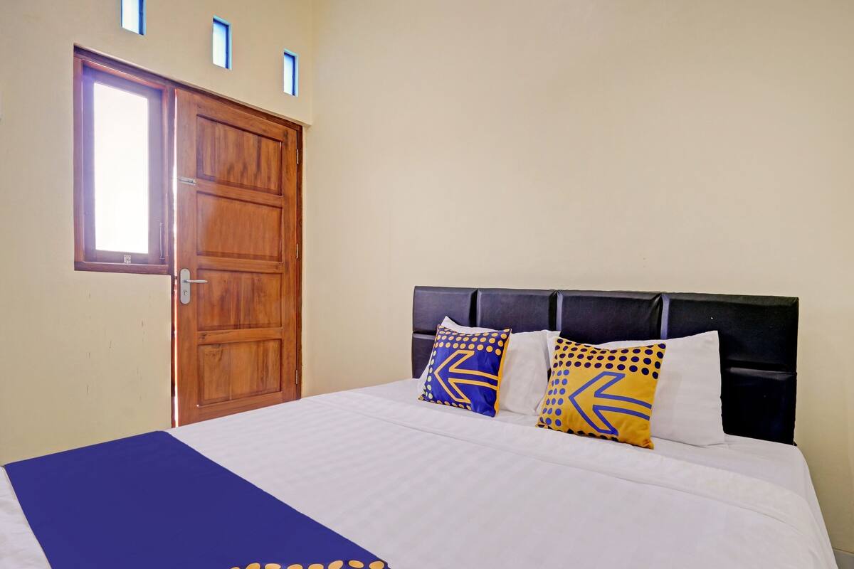 Habitación de hotel con una cama grande, una puerta de madera y una ventana.