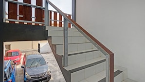 A multi-level building with a staircase connecting the ground floor to the upper level. There are two cars parked on the ground floor. - SPOT ON 90577 Griya Afifah Syariah (Klaten)