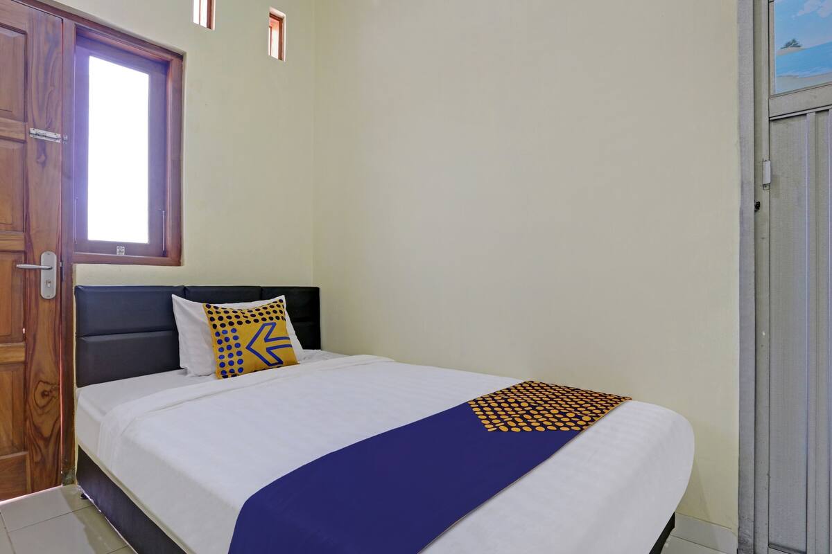 Una habitación de hotel con cama, ventana y puerta.