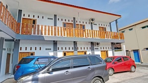A modern building with a balcony, multiple doors, and parked cars. - SPOT ON 90577 Griya Afifah Syariah (Klaten)
