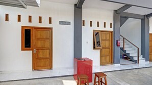 A hallway with wooden doors, a red cabinet, and a staircase. - SPOT ON 90577 Griya Afifah Syariah (Klaten)