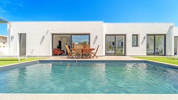 A modern house with a swimming pool, a patio with outdoor furniture, and large sliding glass doors. - WELCS VILLA 167 EMP con piscina privada (Empuriabrava)