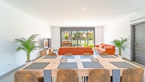 A modern dining area with a long table, six chairs, and two sofas. - WELCS VILLA 167 EMP con piscina privada (Empuriabrava)