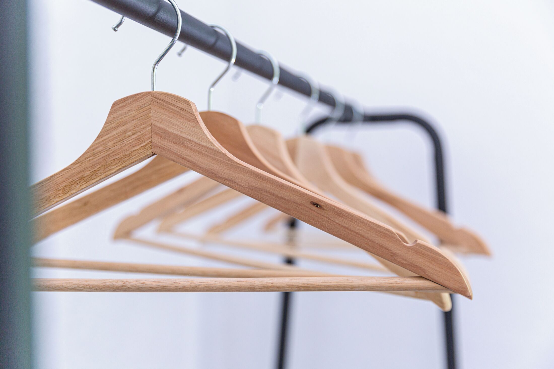 A row of wooden hangers on a metal rack.