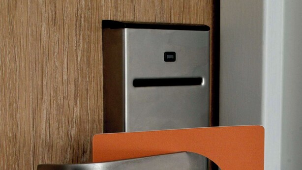 A door with a metal handle and an orange card with text in French. - Kyriad ECO Lille SUD - Noyelles-Godault (Noyelles-Godault)