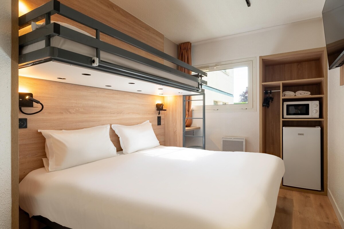 Un dormitorio moderno con cama, armario empotrado, microondas y refrigerador pequeño.