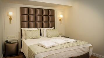 A neatly made bed with a tufted headboard, two bedside lamps, and a small bedside table with a telephone.