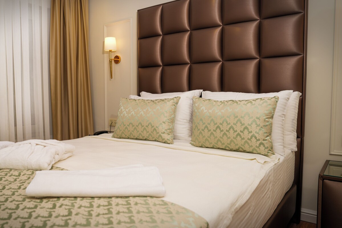 A neatly made bed with two pillows, a bedside lamp, and a patterned bedspread.