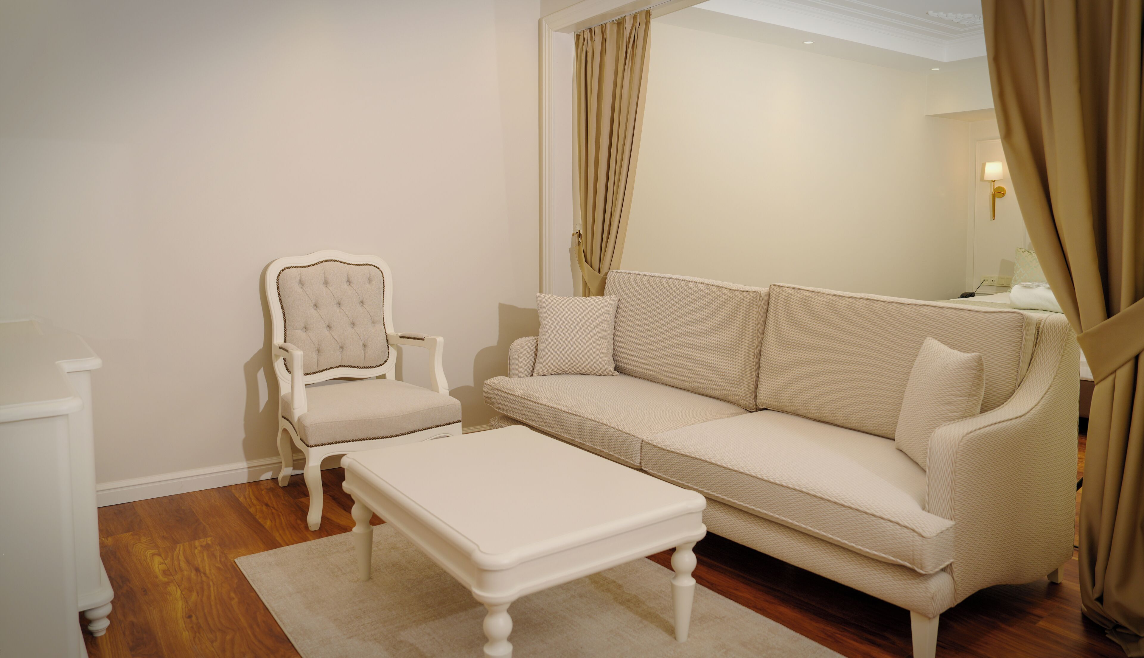 Una habitación con un sofá blanco tapizado, un sillón a juego y una pequeña mesa blanca.