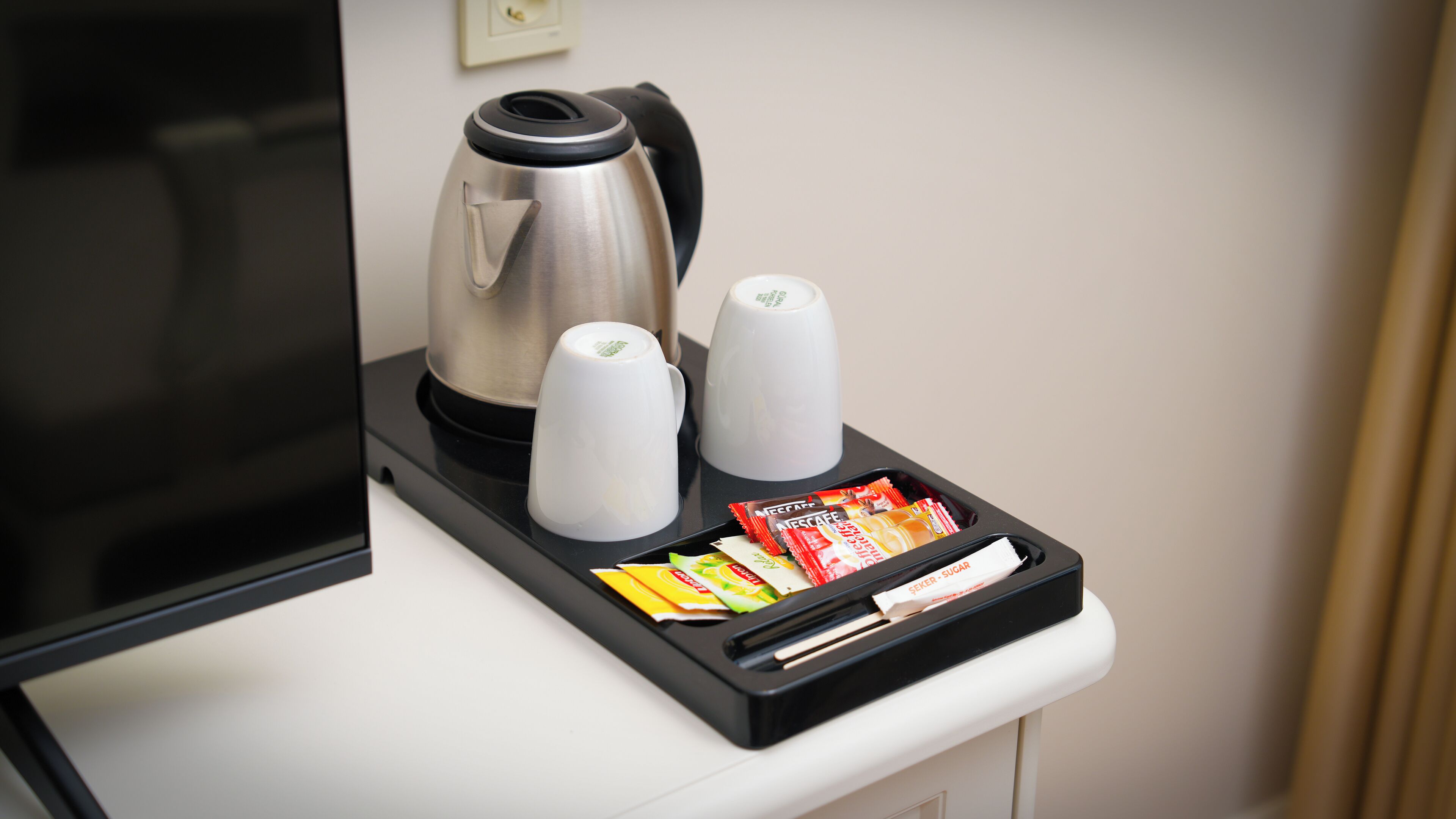 En kaffestation med en kaffebryggare, två koppar och ett fat med kaffepaket.