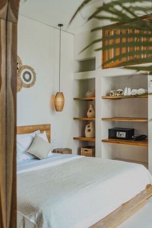 A neatly arranged bedroom with a wooden bed, a hanging woven light fixture, and built-in shelves with various items. - Luana Villa by Betterplace (Canggu)