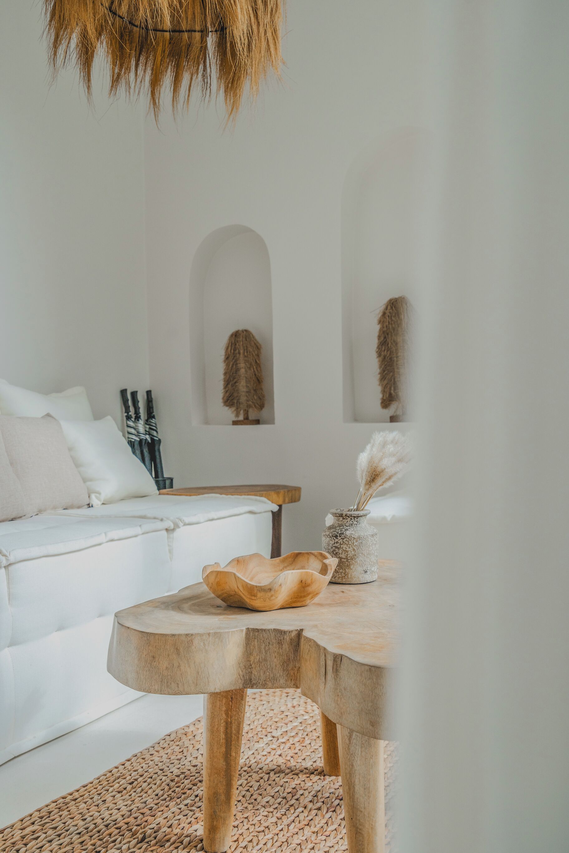 A modern living room with a white sofa, a wooden coffee table, and a woven rug.