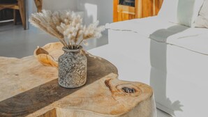 Una sala de estar moderna con una mesa de centro de madera, un sofá blanco y una escalera al fondo.
