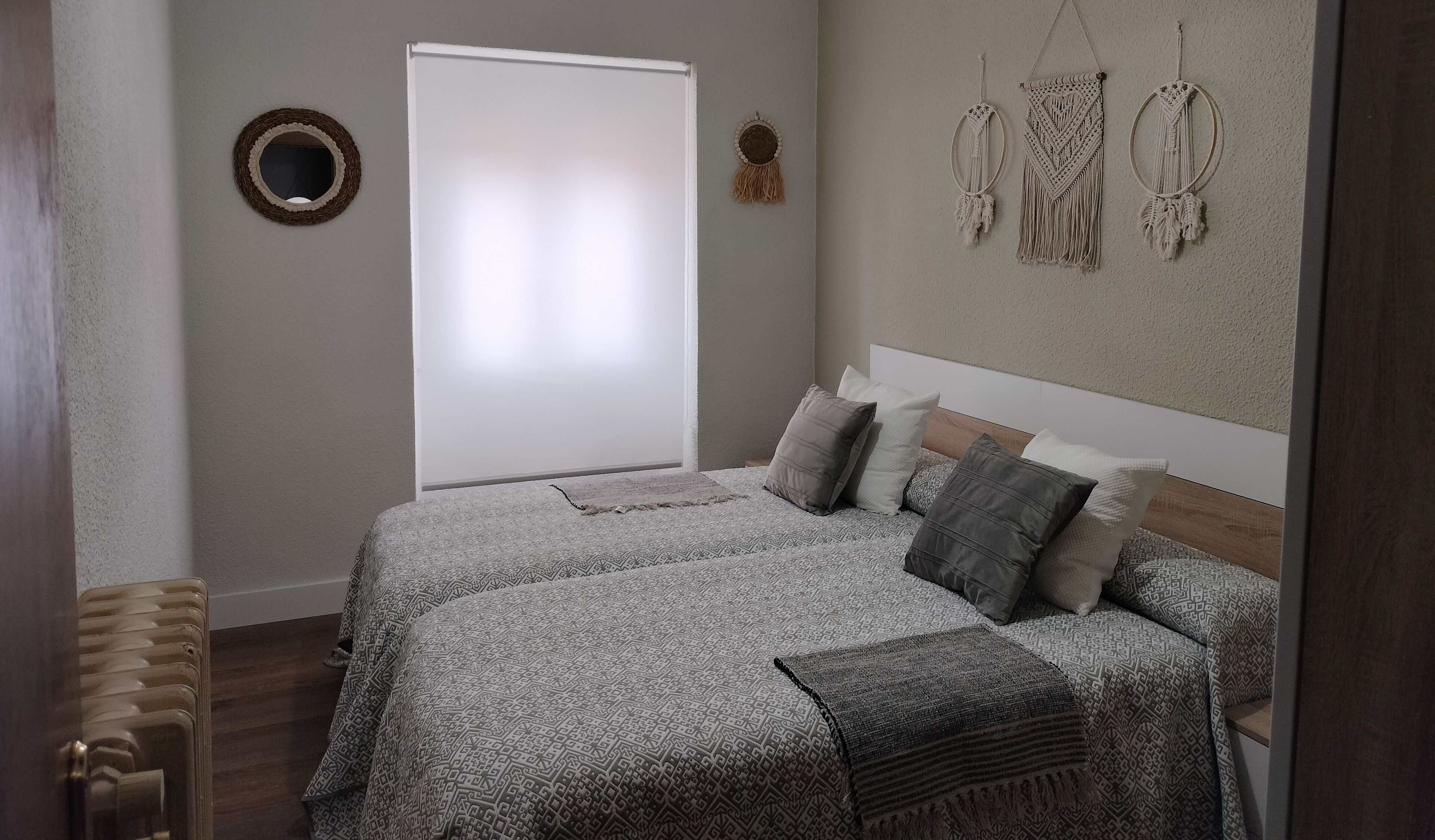 Un dormitorio con cama, ventana y adornos en la pared.