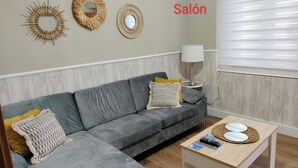 A modern living room with a grey sofa, two side tables, and three wall-mounted mirrors.