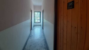 A narrow hallway with a wooden door labeled "210 Fybed" and a window at the end. - Fybed Guesthouse (Semarang)