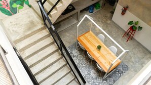 A staircase with a metal railing leading to a room with a wooden table and chairs, a small plant, and a fire extinguisher on the wall. - Fybed Guesthouse (Semarang)