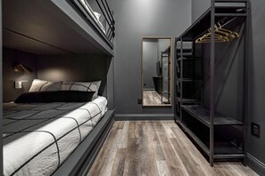 A compact bedroom with a bunk bed, a walk-in closet with hanging space, and a large mirror. - The Downtown Derby Stay (Louisville)