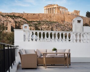 Un balcone con mobili in vimini e vista su rovine antiche.