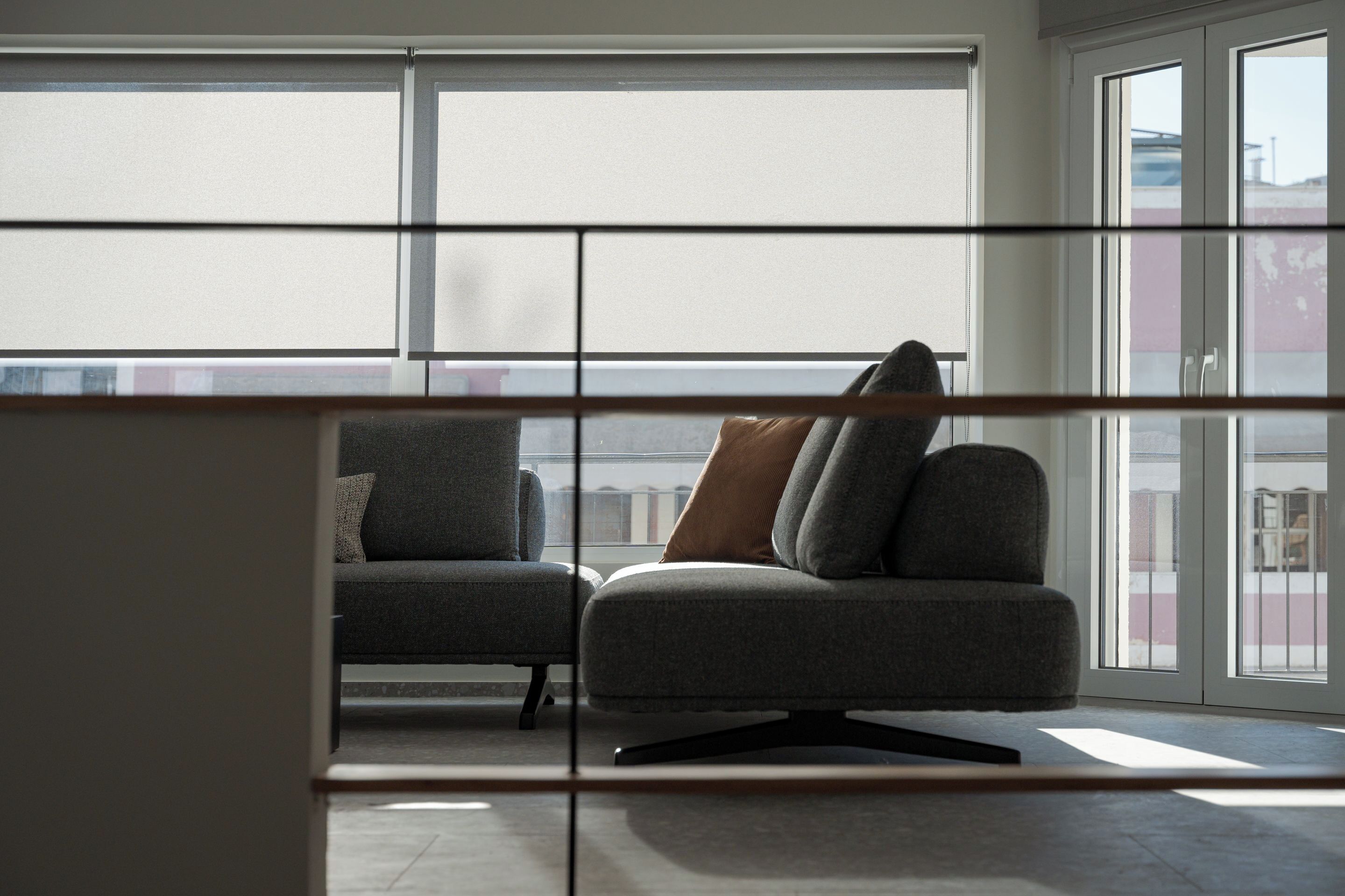 Un salon moderne avec un canapé et des fauteuils, de grandes fenêtres et une vue sur le paysage urbain.