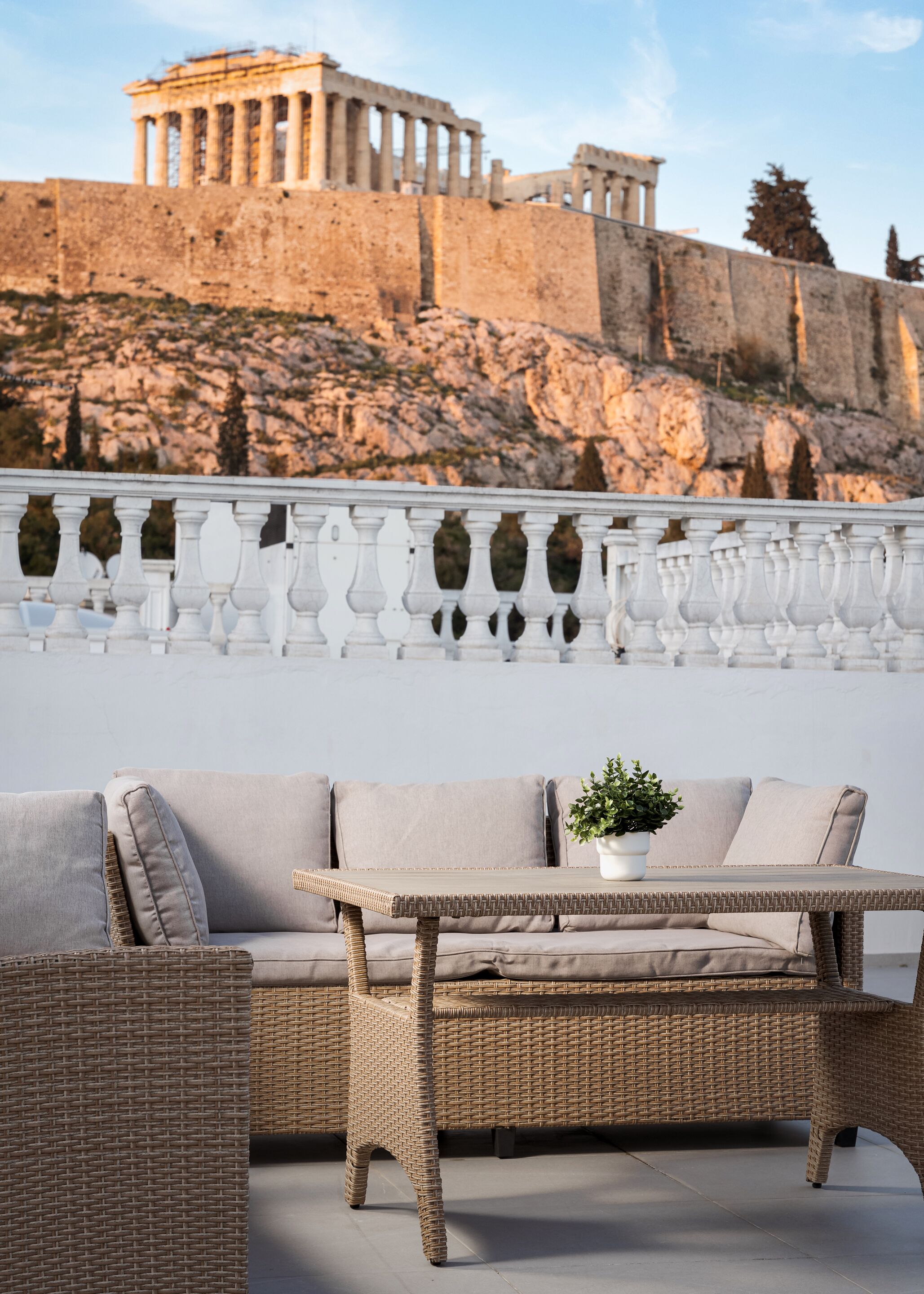 An outdoor seating area with wicker furniture and a view of ancient ruins in the background.