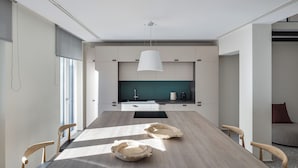 A modern kitchen with a long dining table, wooden chairs, and a pendant light. - Acropolis Iconic Estate (Athens)
