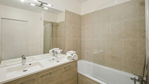 A modern bathroom with a large mirror, a sink, a bathtub, and a shower. - Chic and comfortable apart with Parking and balcony (Bezons)