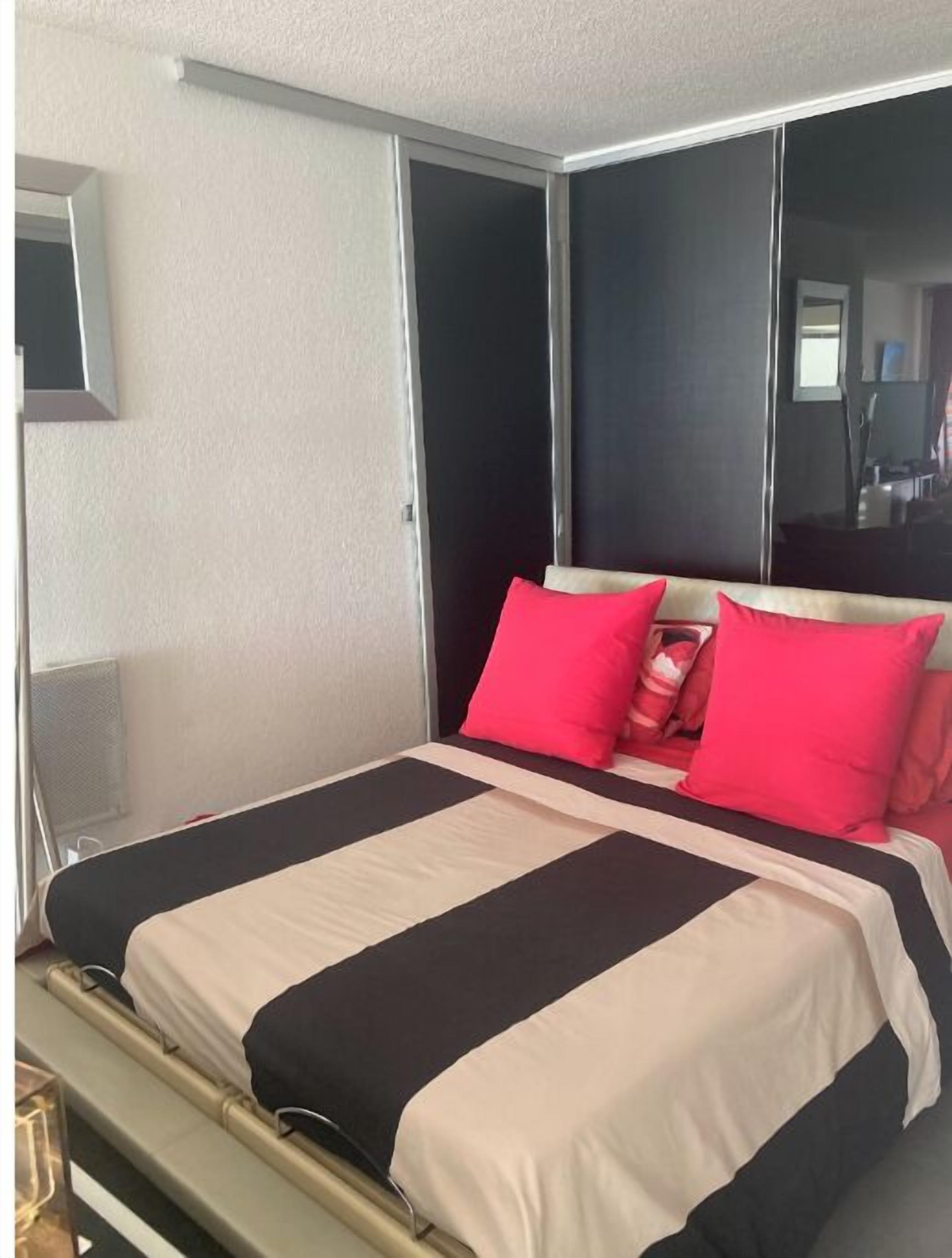 Une chambre d’hôtel avec un lit, un miroir et une fenêtre.