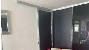 Quarto de hotel com cama, espelho e janela.